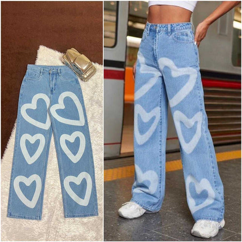 Light blue jeans with white heart patterns on a textured surface and worn by a person in an urban setting.